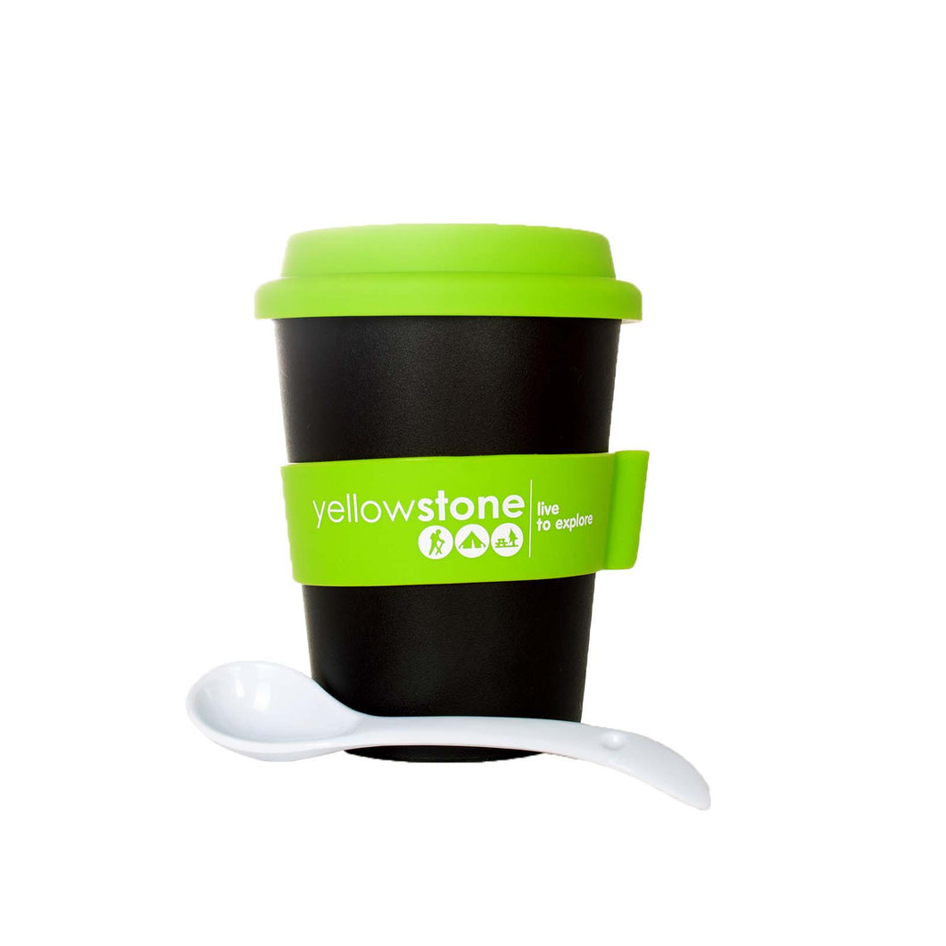 Black travel cup with green silicone lid and sleeve. It is accompanied by the included white plastic spoon