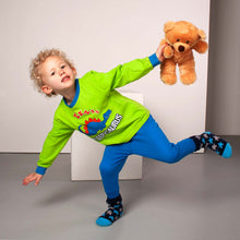 Load image into Gallery viewer, Young boy wearing green and blue dinosaur pyjamas while holding a brown teddy bear
