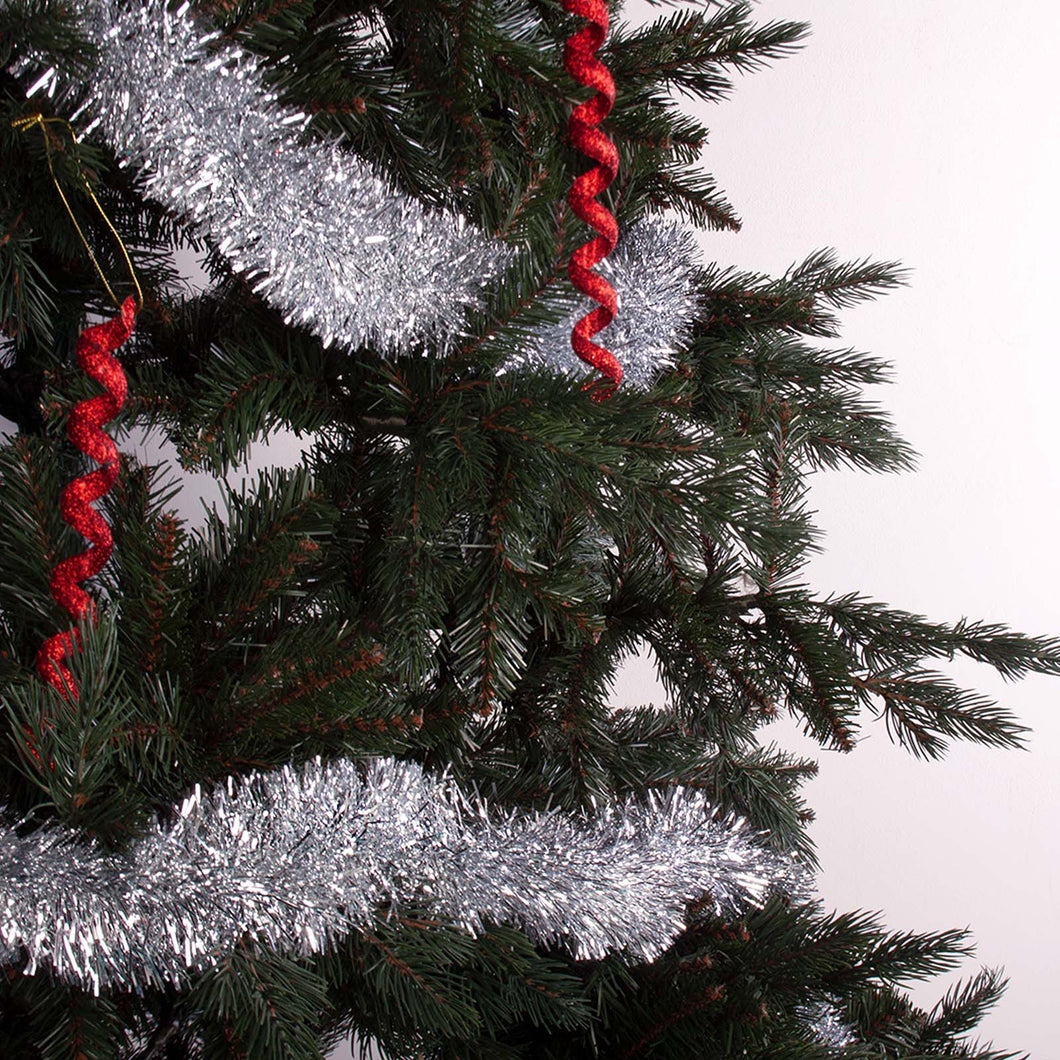 Metallic silver tinsel wrapped around a tree decorated with hanging baubles